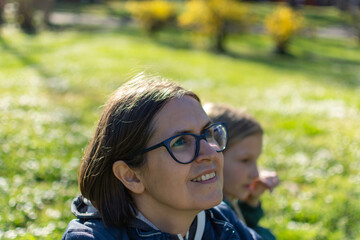 A portrait of mother with a small daughter in spring nature at sunset.