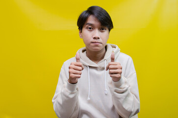 handsome attractive Asian man smiling happily and giving thumbs up as compliment, isolated over...
