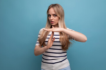 close-up of a girl in casual clothes with a hand gesture of the letter t on a blue isolated background