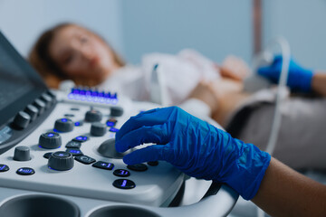 Close-up of the hands of a female ultrasound doctor in gloves during the examination of a patient.