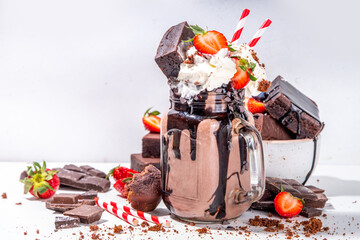 Double chocolate taste milkshake. Crazy shake with brownie taste, chocolate sauce, whipped cream topping and fresh strawberry, summer sweet loaded sweet dessert drink copy space - obrazy, fototapety, plakaty