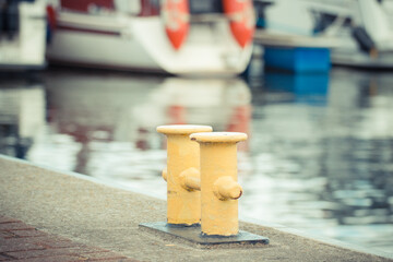 Yellow bollards on wharf using for anchorage of yachts. Detail of sailboat. Transportation