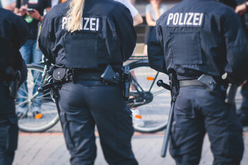 German police squad formation in protective gear with "Police" logo on uniform maintain public order after football game and political protest rally in the streets of Berlin city center, Germany