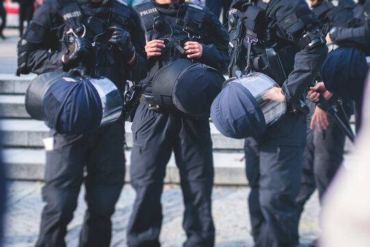 German police squad formation in protective gear with "Police" logo on uniform maintain public order after football game and political protest rally in the streets of Berlin city center, Germany