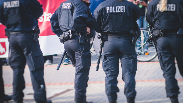 German police squad formation in protective gear with "Police" logo on uniform maintain public order after football game and political protest rally in the streets of Berlin city center, Germany