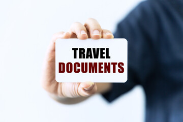 Travel documents text on blank business card being held by a woman's hand with blurred background. Business concept about travel documents.