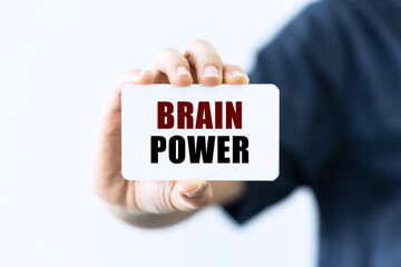 Brain power text on blank business card being held by a woman's hand with blurred background. Business concept about brain power.