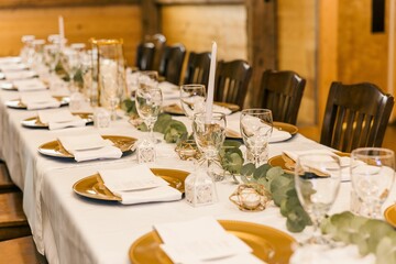 Set table with golden plates and wooden chairs decorated for a wedding party