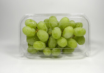 A box of American seedless green grapes packed in a transparent plastic box, on a white background