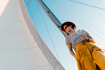 Attractive woman drinking wine and relaxing on sailboat during sailing in sea