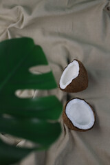 tropical ripe coconut halves with white flesh and green mint leaves on a light beige fabric. for banners, screensavers, postcards, labels, signboards, napkins, lunchboxes, etc.