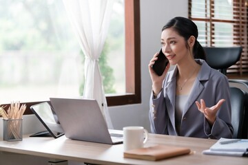 Creative Asian young woman working on laptop in her office.