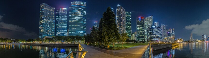 View over Marina Bay in Singapore durnig sunset with light illuminations in water