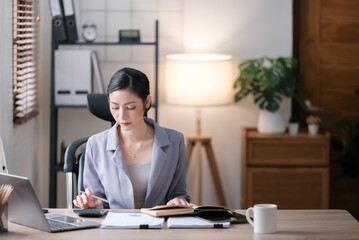 Creative Asian young woman working on laptop in her office.