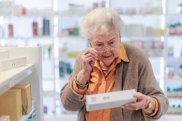 Senior woman reading text on the medication box.