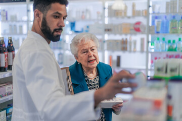 Young pharmacist helping senior woman to choos medication.