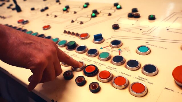 Handheld following shot of a workers finger pushing factory console buttons. Factory being switched on. 4k.