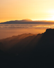 paisaje de montaña en atardecer con cielo dorado y sol creando espectaculares rayos entrando en el oscuridad