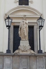 Vertical shot of female statue with two street lanterns in front of the gate of St. Hyacinths Church