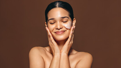 Woman with smooth skin enjoys using a hydrogel patch on her skin, an undereye mask used for...