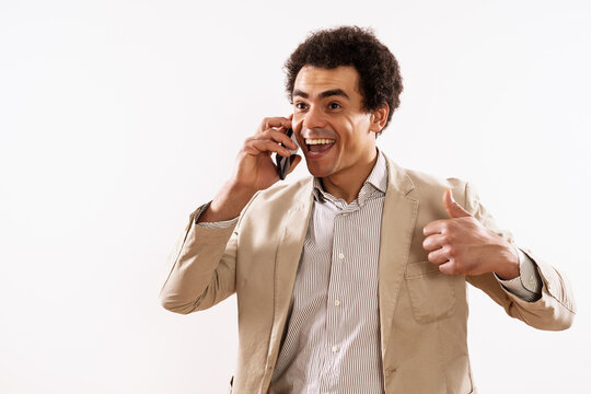 Image of happy businessman talking on the phone and showing thumb up.	