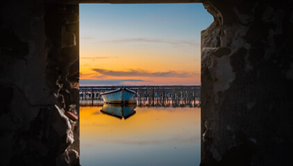 Vue d'un coucher de soleil à travers la fenêtre d'une cabane de pêcheur sur un étang de ...
