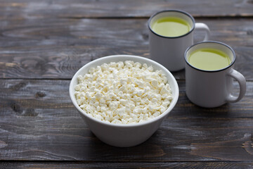 Fresh homemade grained cottage cheese and whey on wooden background