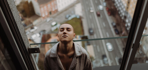Top view of young unhappy woman with cancer sitting in a window.