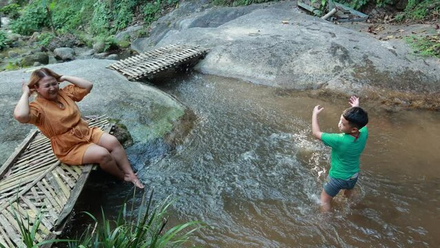 Slow motion Asian fat woman mother Tourist stiing on bamboo bridge handmade with her son at vacation holiday natural waterfall. Tourism travel and vacation concept