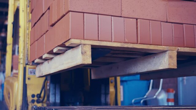 Forklift carrying a load of bricks then offloading on conveyor. 4k.
