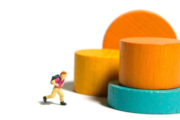 Miniature people toy figure photography. A boy kindergarten student playing Montessori wooden block. Isolated on white background