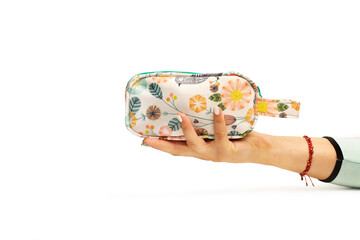 Mano de mujer sosteniendo un bolso de mano con motivos florales de colores sobre un fondo blanco liso y aislado. Vista de frente y de cerca. Copy space