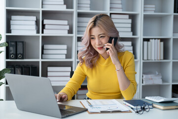 Young professional businesswoman having a phone call with her boss while sitting in the office room.