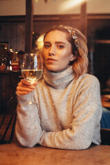 beautiful young blonde woman with a glass of white wine in a restaurant