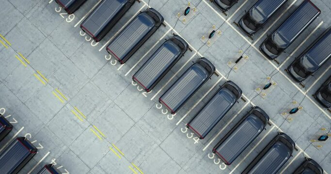 Drone overhead shot, huge fleet of electric EV delivery vans are being charged in company parking garage