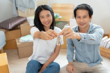 Moving house, relocation. Couple hold key house keychain in new apartment, inside the room was a cardboard box containing personal belongings and furniture. move in the new apartment or condominium