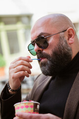 bald bearded fashionable middle aged man eating ice cream