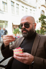 bald bearded fashionable middle aged man eating ice cream