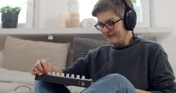 Creative Aged woman learns to play keys at home
