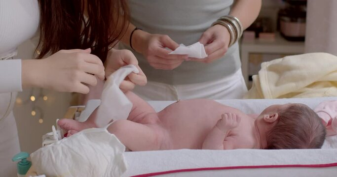 The hands of a young mother and partner wipe the body of a newborn child with a napkin. Simple hygiene when changing a diaper. Body and skin care. 17.09.2022 Konevova, Prague, Czech Republic