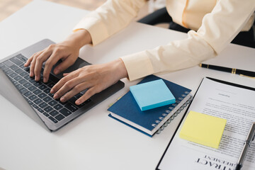 Close up view of businesswoman typing on laptop computer while working in her office room.