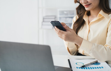 Beautiful businesswoman using smartphone while sittng at her office desk.