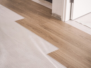 A technician is cutting luxury vinyl floor tiles with a cutter to lay the floor before placing it on the leveling foam..