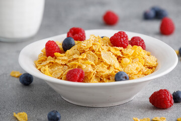 Tasty cereal with blueberries and raspberries on a grey table