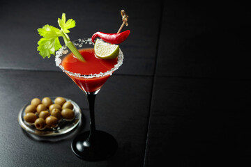 Bloody Mary cocktail with celery, lime, red pepper, and green olives.
