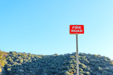 Fire Road Sign Against Blue Sky and Dense Forest