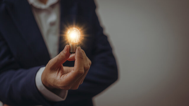 Business idea concept, Hands of business woman in suit holding light bulb with innovation and inspiration creative agency new beginning Analyzing data