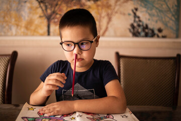 A bored little boy student inserted a pencil into his nose. The concept of ADHD - obrazy, fototapety, plakaty