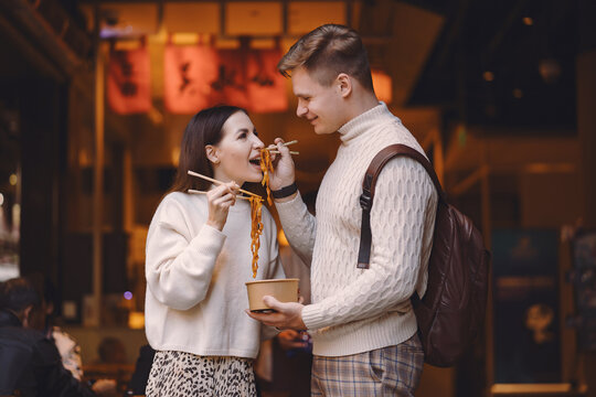 newlywed couple eating noodles with chopsticks in Shanghai outside a food market