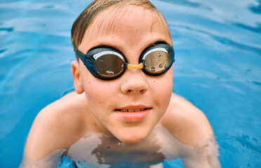 Smiling boy portrait in swimming goggles, Child swim in the pool